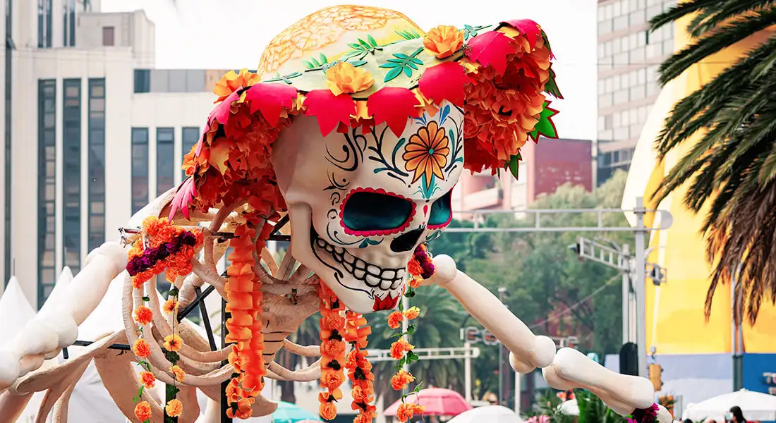 Figura monumental de calavera con sombrero y flores en una celebración urbana