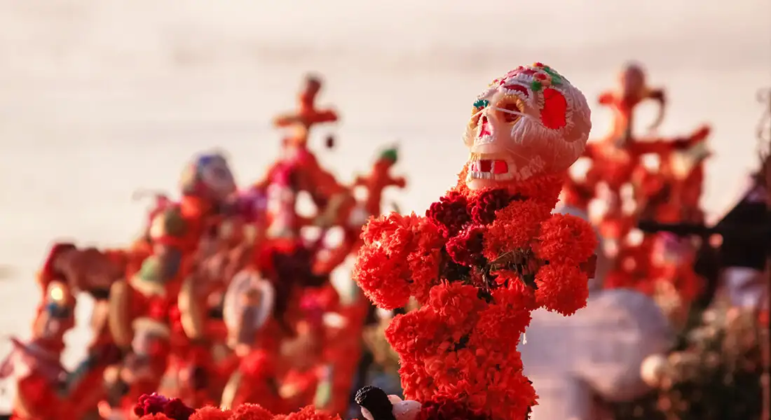 Figura de calavera rodeada de flores y adornos de Día de Muertos