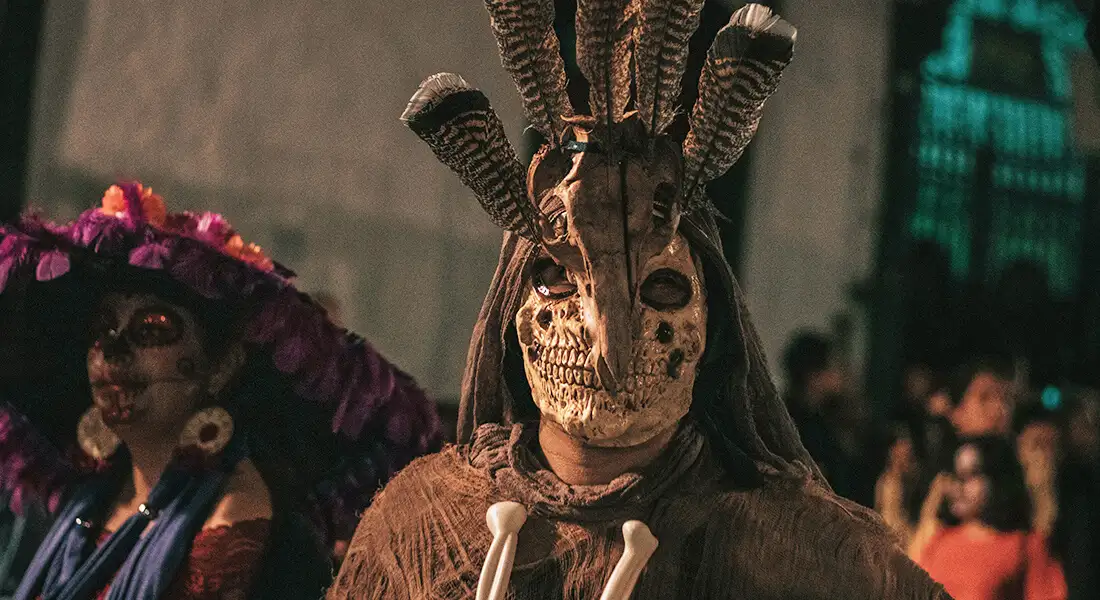 Participantes con máscaras y vestuario durante una celebración de Día de Muertos